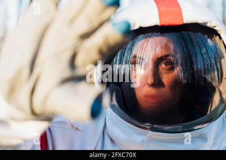 Female astronaut wearing space helmet shielding face from sunlight Stock Photo
