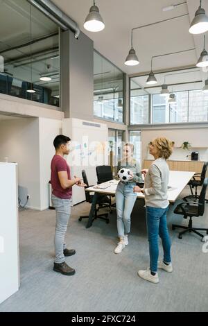 Male and female entrepreneurs playing soccer ball in coworking office Stock Photo