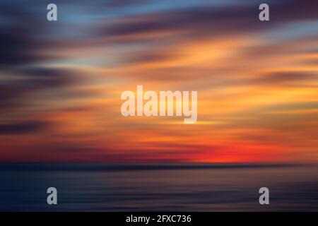 Motion blurred ocean and colorful sky at sunset. Abstract natural background with copy space. Stock Photo