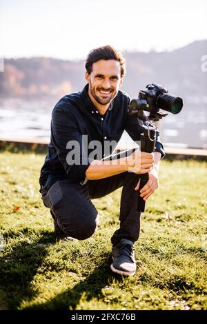 Smiling handsome man holding gimbal on sunny day Stock Photo