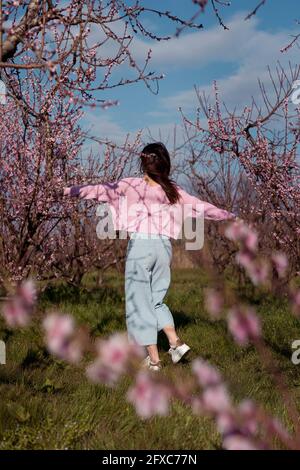 Woman enjoying in peach field during sunny day Stock Photo