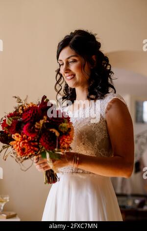 Beautiful bride holding bouquet in domestic room Stock Photo