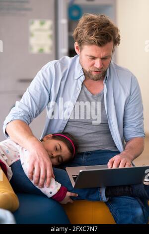 Businessman taking care of girl while using laptop at home Stock Photo