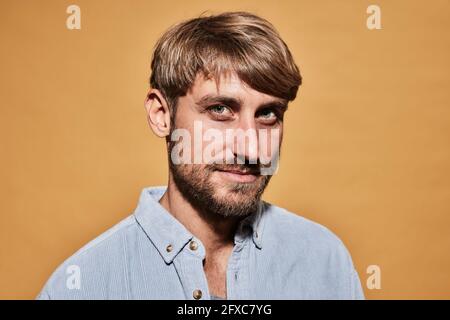 Handsome man with blond hair staring in front of wall Stock Photo
