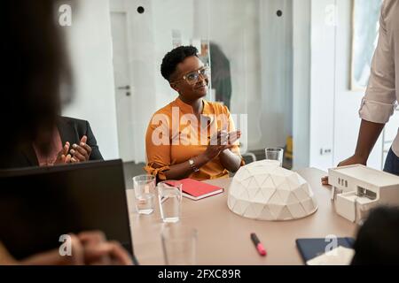 Business people clapping while looking at male architect at coworking office Stock Photo