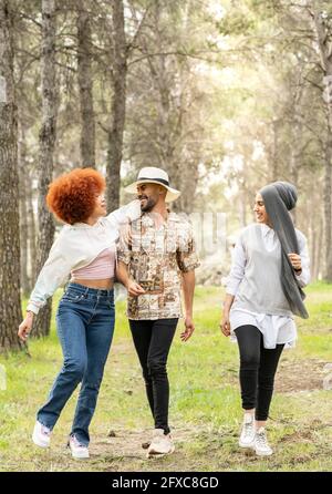 Happy female friends with young man having fun during picnic in forest Stock Photo