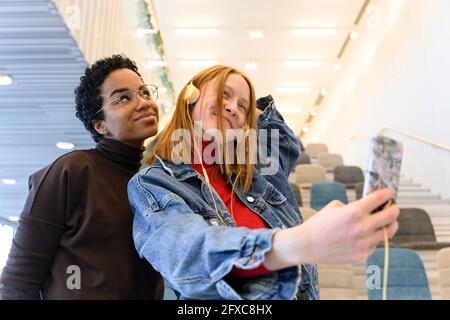 Multi-ethnic female friends making faces while taking selfie Stock Photo