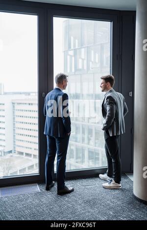 Business people discussing while standing by window in office Stock Photo