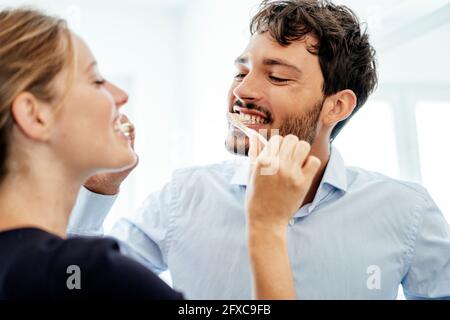 Young couple brushing each other's teeth at home Stock Photo