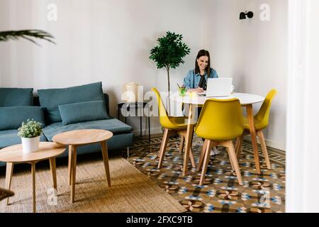 Smiling female entrepreneur working at desk in home office Stock Photo