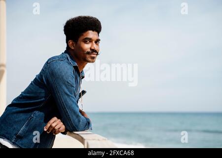 Handsome man leaning on railing by sky Stock Photo