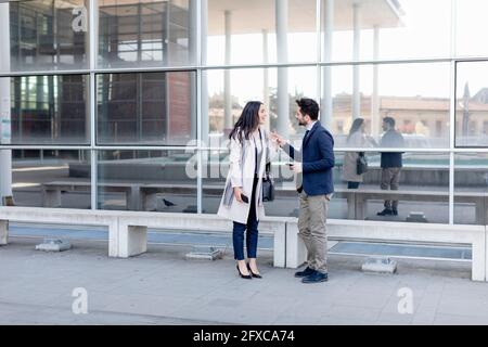 Business couple talking while standing on footpath Stock Photo