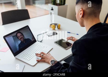 Female entrepreneur using digital tablet during video call through laptop at office Stock Photo