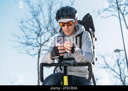 Delivery man leaning on bicycle while using smart phone Stock Photo