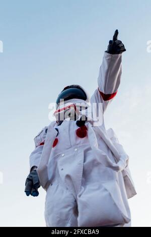 Young female astronaut pointing while wearing space suit Stock Photo