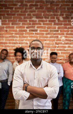 Confident male professional with coworkers in background at office Stock Photo