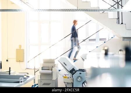 Businesswoman walking on steps in printing workshop Stock Photo
