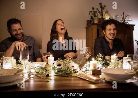 Happy male and female friends sitting at dining table during birthday celebration Stock Photo