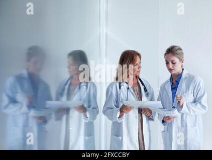 Female doctors discussing over documents in hospital Stock Photo