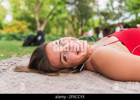 Happy young woman lying on blanket in park Stock Photo