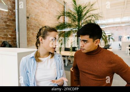 Male and female business professionals discussing at coworking office Stock Photo