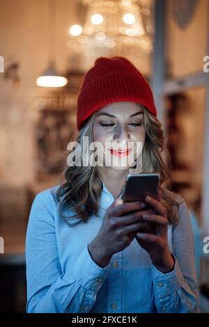 Mid adult businesswoman wearing knit hat using mobile phone Stock Photo