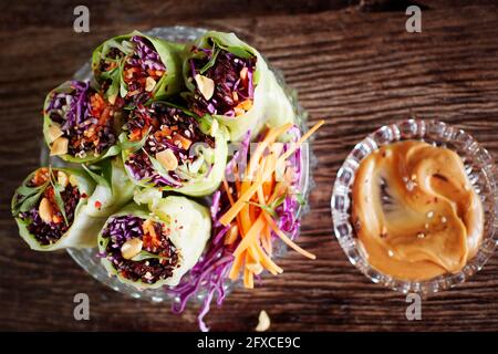 Dipping bowl with peanut butter and cabbage rolls with black rice, sesame seeds, carrot and red cabbage Stock Photo