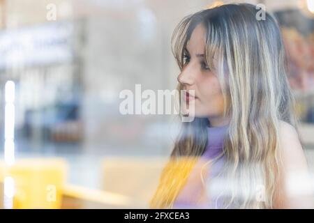 Beautiful young woman seen through glass of restaurant Stock Photo