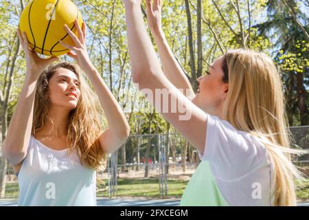Young women playing basketball on sunny day Stock Photo