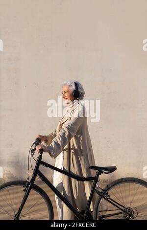 Smiling woman looking away while standing with bicycle Stock Photo