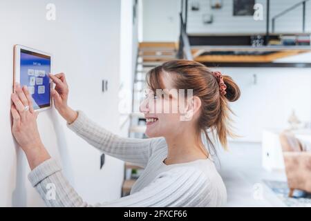 Happy young woman looking at control panel in home Stock Photo