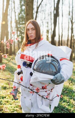 Young female astronaut with space helmet standing in forest Stock Photo