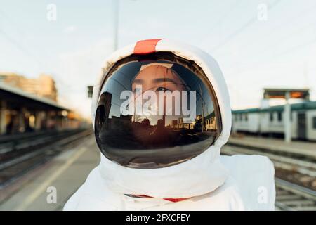 Thoughtful female astronaut in space helmet looking away during sunset Stock Photo