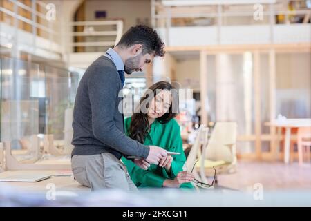 Young male and female professionals discussing over digital tablet at office Stock Photo