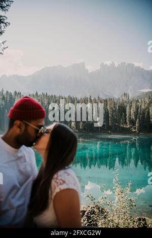 Young couple kissing at Carezza lake in South Tyrol, Italy Stock Photo