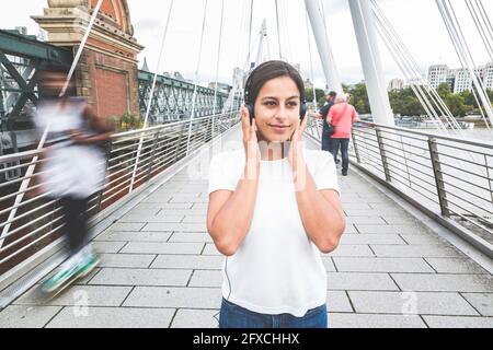 Young woman contemplating while listening music on bridge Stock Photo