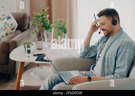 Smiling handsome man staring intently at laptop screen at home Stock Photo
