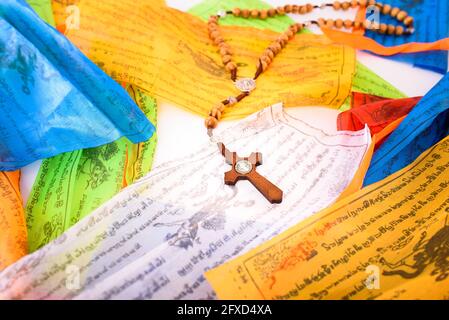 Catholic cross on colorful Tibetan Sanskrit banners with religious prayers Stock Photo