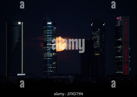 Madrid, Spain. 26th May, 2021. The full moon of May also known as Flower Moon rises over the Four Towers Business area skyscrapers. A rare simultaneous occurrence of a blood supermoon and lunar eclipse will be visible in some parts of the world. Credit: Marcos del Mazo/Alamy Live News Stock Photo
