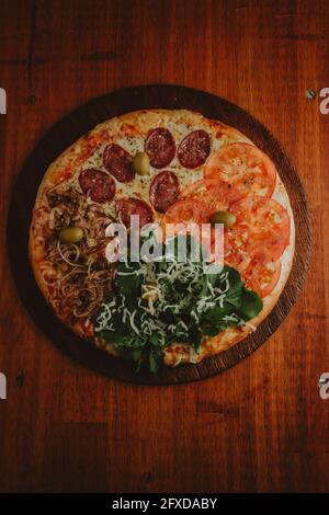 foreground four seasons pizza with tomatoes, salami, onion and arugula Stock Photo