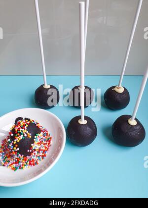 Five chocolate cake pops standing one in sprinkles white sticks Stock Photo