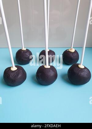 Six chocolate cake pops standing on blue table white vertical sticks Stock Photo