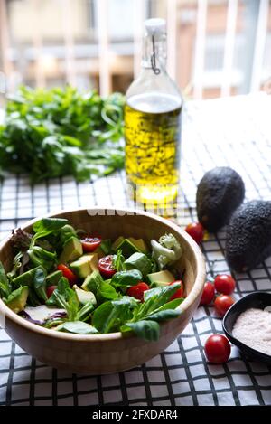 Fresh salad with cherry tomatoes, avocados, lamb's lettuce and olive oil, on a checkered tablecloth. Stock Photo