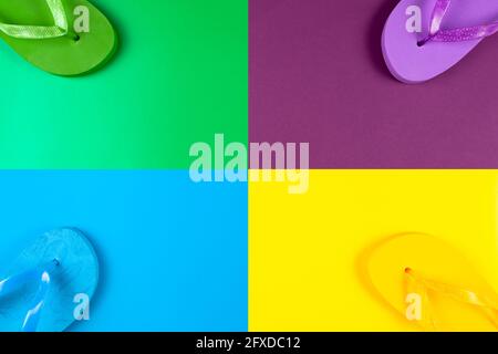 blue, green, yellow, purple rubber flip flops on multicolored backgrounds, place under text Stock Photo