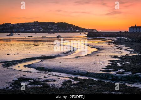 UK Weather. Instow, North Devon, England. Wednesday 26th May 2021. After a warm and sunny day in North Devon, the sun sets behind the quay at Instow as the lights flicker on in neighbouring village of Appledore on the other side of the River Torridge estuary. Credit: Terry Mathews/Alamy Live News