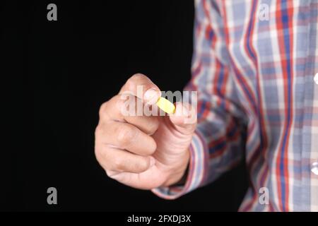 young man hand holding medical pills isolated on black  Stock Photo