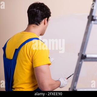 The young contractor employee applying plaster on wall Stock Photo