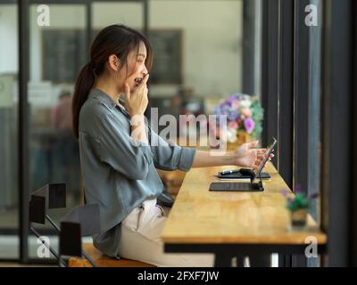 Side view of excited young female looking at digital tablet screen, feeling amazed while using digital tablet Stock Photo