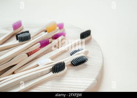 Colorful eco friendly bamboo toothbrushes on wooden tray, dental care with zero waste concept, sustainable lifestyle Stock Photo