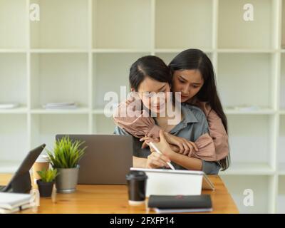 Portrait of two female office workers hugging in office room, happy friends, friendship Stock Photo